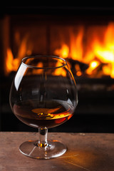 a glass of cognac in front of fireplace