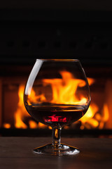 a glass of cognac in front of fireplace
