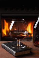 a glass of cognac in front of fireplace
