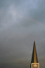 Kirchturm mit Regenbogen / Der Uhrenturm einer Kirche am Abend im Sonnenuntergang und mit einem...