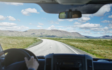 view from the car cabine on a plot of asphalt road in a bright sunny mountain landscape