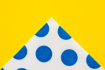 Folded paper napkin with blue polka-dots on a yellow table