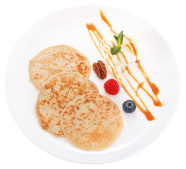 Serving pancakes with ice cream and fresh berries on the plate. Decorated with caramel syrup....
