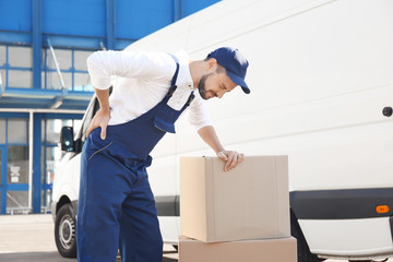 Delivery man suffering from pain after moving heavy box near car