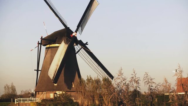 4K Traditional old Dutch rustic windmill working. Netherlands. European historical landmark. Farm mill spinning slowly.