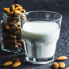 Vegan almond milk and nuts on dark concrete background. Selective focus, space for text, close up.