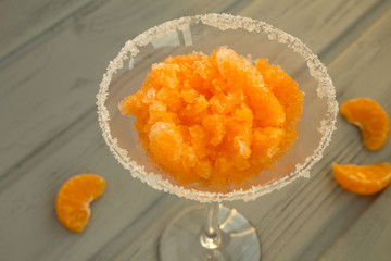 Frozen juice with mandarins in the wineglass on the grey  wooden background