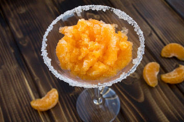 Frozen juice with mandarins in the wineglass on the wooden background