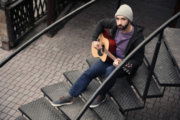 Fototapeta na wymiar Young hipster man playing guitar outdoors