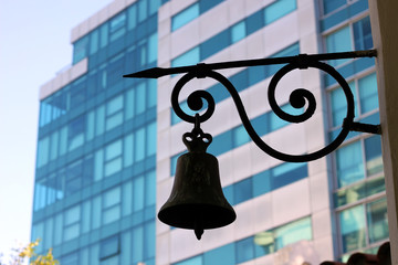 Obraz premium Old black bell on background of modern building
