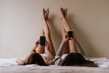 Gorgeous friends using her mobiles in the bedroom.