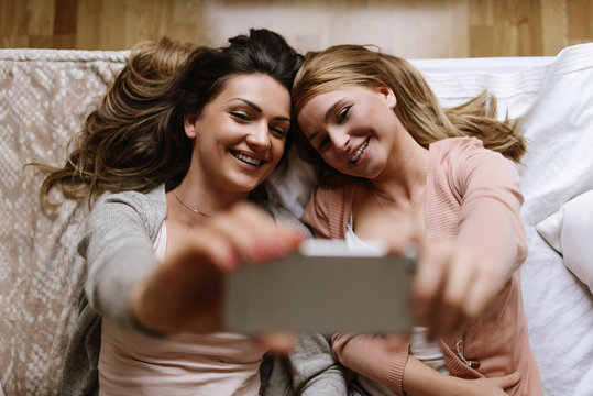 Gorgeous friends taking a selfie in the bedroom.