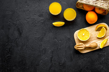 Squeeze juice from oranges. Juicer and slices of oranges on black background top view copy space