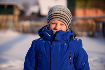 Child in winter clothes outside the city on the background of a snowy winter landscape.