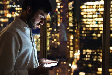 Young businessman checking his phone on an office at night