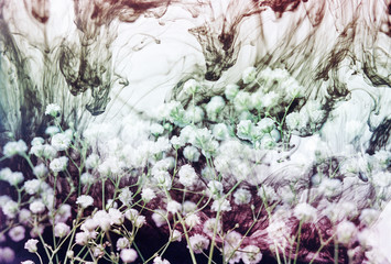 Multiple exposure of white flowers and colorful ink swirls