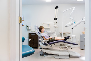 little boy sitting on chair at the dentist