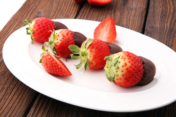 Chocolate dipped strawberries at dessert bar on white plate.
