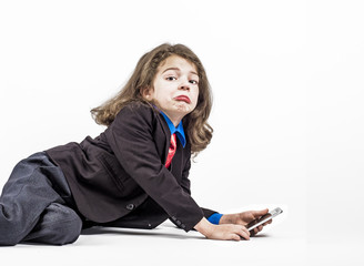Little smiling boy in the clothes of a businessman playing games or surfing internet on digital smartphone. White background.