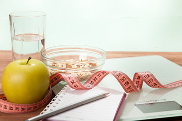 Healthy diet, fitness and weight loss concept. Weights, roulette, fruit, oatmeal, an open notebook and a pencil on the table.