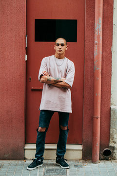 Young man with tattooes stading in front of his house