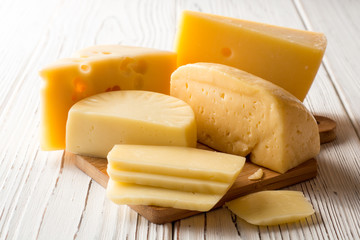 Various types of cheese on white wooden table.