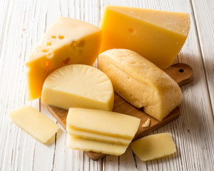 Various types of cheese on white wooden table.