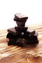 Dark brown chocolate pieces, stacks culinary wooden background.
