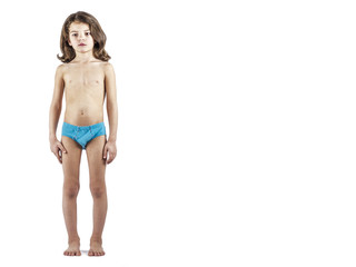 Cute boy in swimming trunks doing gymnastic exercises. White background.