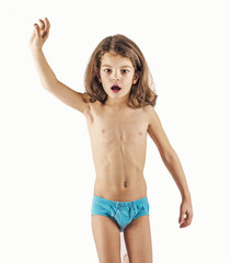 Cute boy in swimming trunks doing gymnastic exercises. White background.