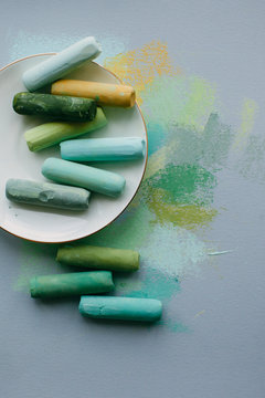 From above shot of soft pastel sticks on porcelain saucer on abstract pastel drawing