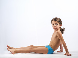 Cute boy in swimming trunks doing gymnastic exercises.