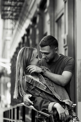 Young couple dressed in casual style poses before a steel fence on the New York street