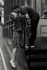 Young couple dressed in casual style poses before a steel fence on the New York street