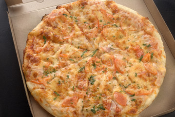 delicious pizza with ham, pepperoni and cheese.Pizza in a cardboard box top view