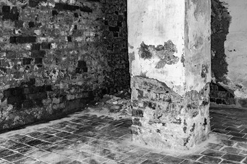 Fototapeta premium part of the room with destroyed brick walls, rectangular column with crumbling plaster at the base