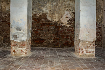 part of the room with destroyed brick walls, rectangular two columns with crumbling plaster at the base