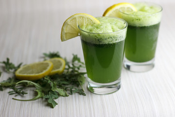 Fresh green juice in two glasses. Wild rocket, parsley and lemon.