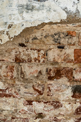 texture of an old wall of an ancient building with a ruined plaster layer and cracked red bricks