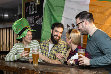 Group of people in pub with beers on hands celebrate Irish traditional St Patrick day