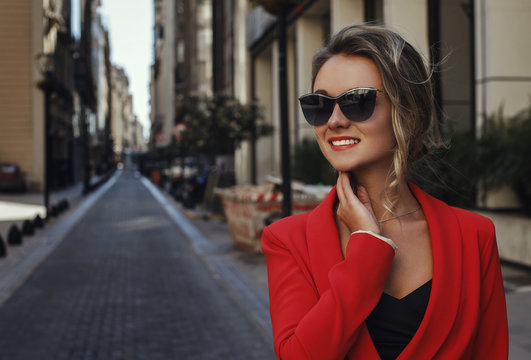 woman in red suit and sun glasses smiling outdoors