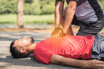 sport man makes first aid for his friend with heart attack in the park