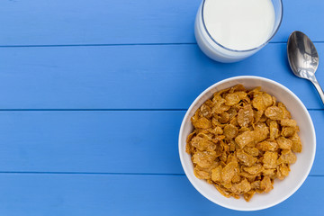 Cornflakes breakfast cereal bowl with milk on wood table background
