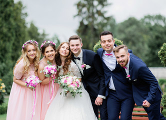 Pretty brides and their stylish friends pose in a green summer park