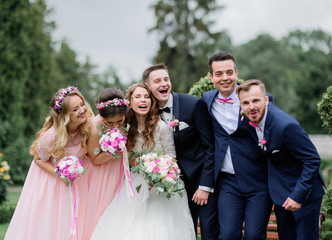 Pretty brides and their stylish friends pose in a green summer park
