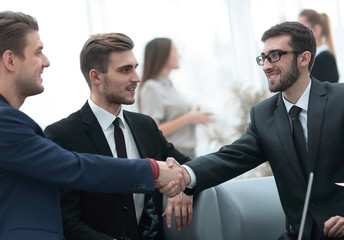 Partners concluding deal and shaking hands in the presence of team members