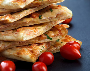 slices of delicious pizza with cheese and ham on a black background