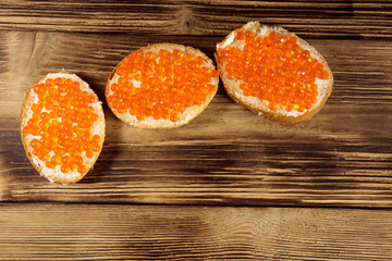 Sandwiches with butter and red caviar on wooden table