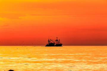 Fischerboot fährt im Glanz der untergehenden Sonne im Sonnenuntergang