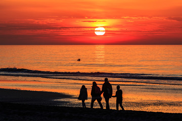 Familie spaziert am Strand beim Sonnenuntergang